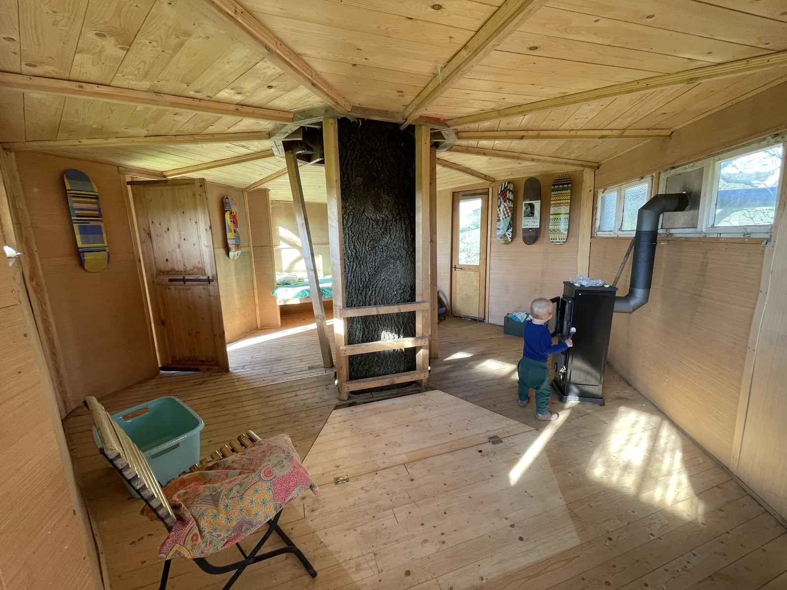 Innenraum des Baumhauses mit Baumstamm und Ofen