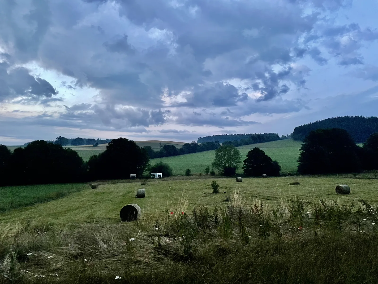 Weite Landschaft mit Strohballen in der Dämmerung